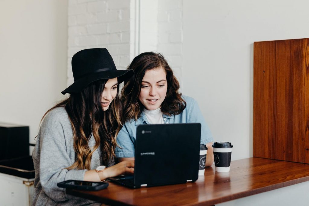 Dos mujeres sentadas juntas, ocupadas delante de un portátil, colaborando o trabajando en un proyecto
