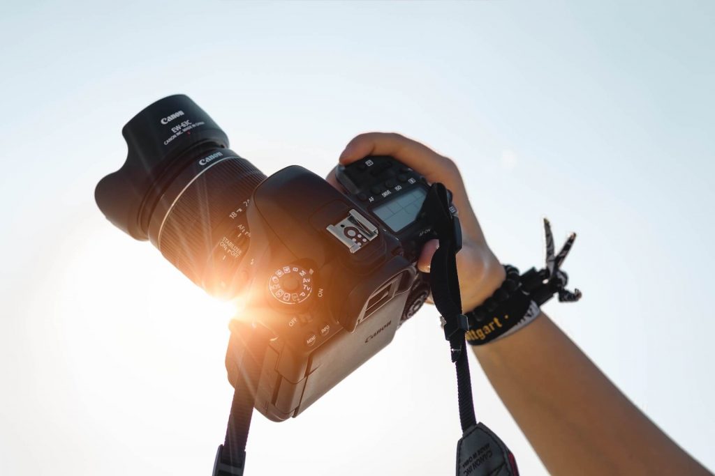 Una cámara DSLR elevada frente al sol, capturando la belleza de la luz natural y la fotografía